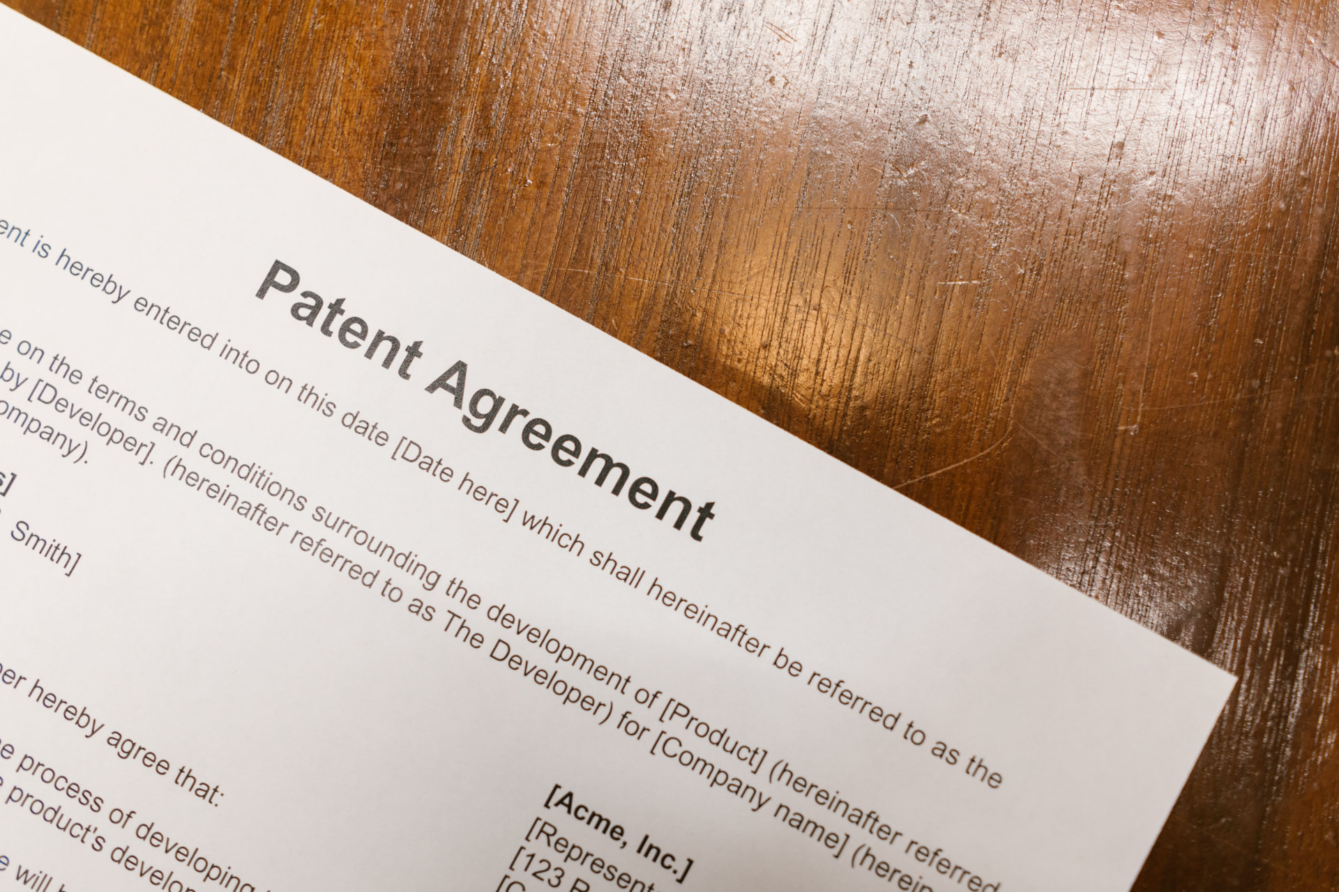 Close-up of a printed patent agreement document lying on a wooden desk.