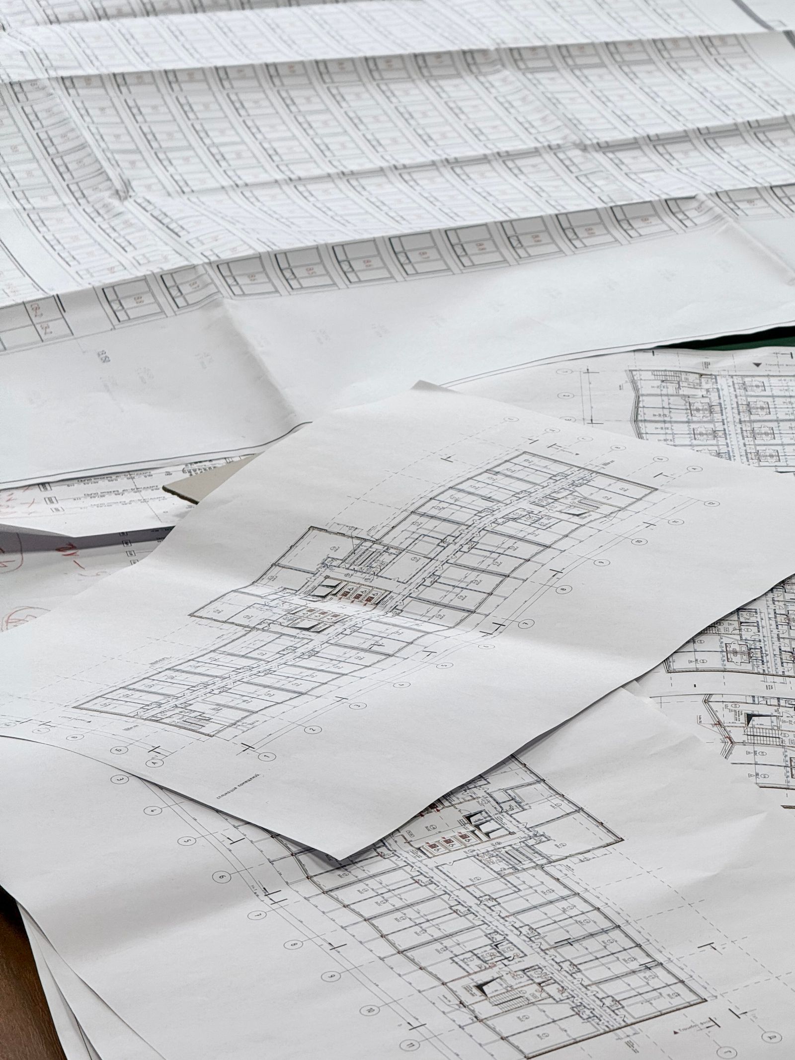 Layered architectural and technical blueprints on a desk.